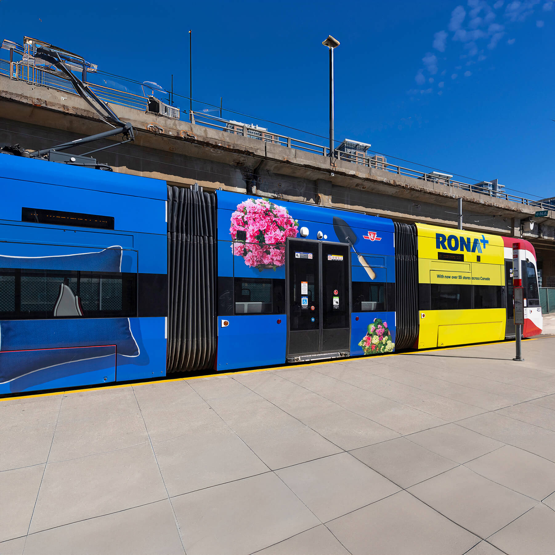 Exterior view of a tramway wrapped with RONA spring advertising, showcasing colorful outdoor branding.