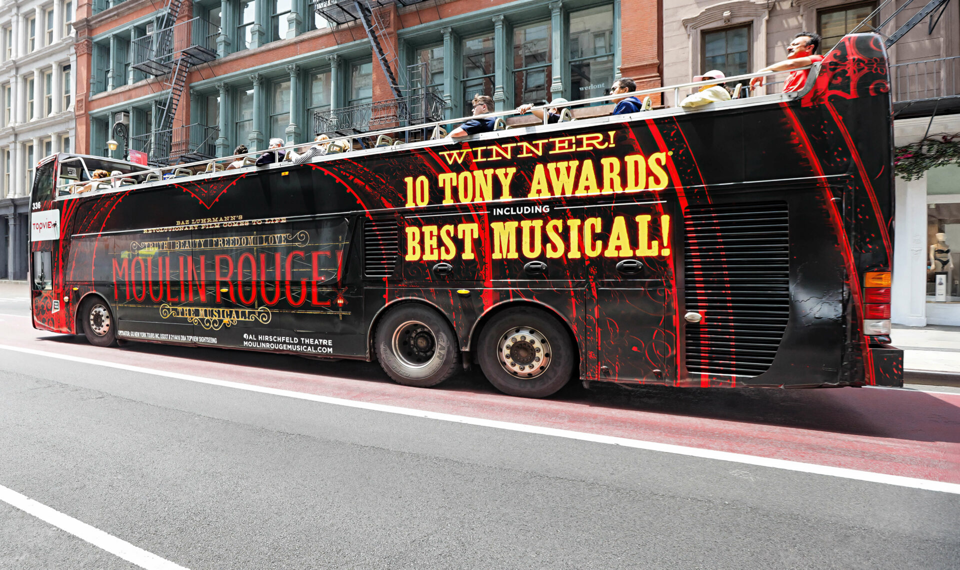 Bus wrapped with Moulin Rouge branding and Tony Award highlights.