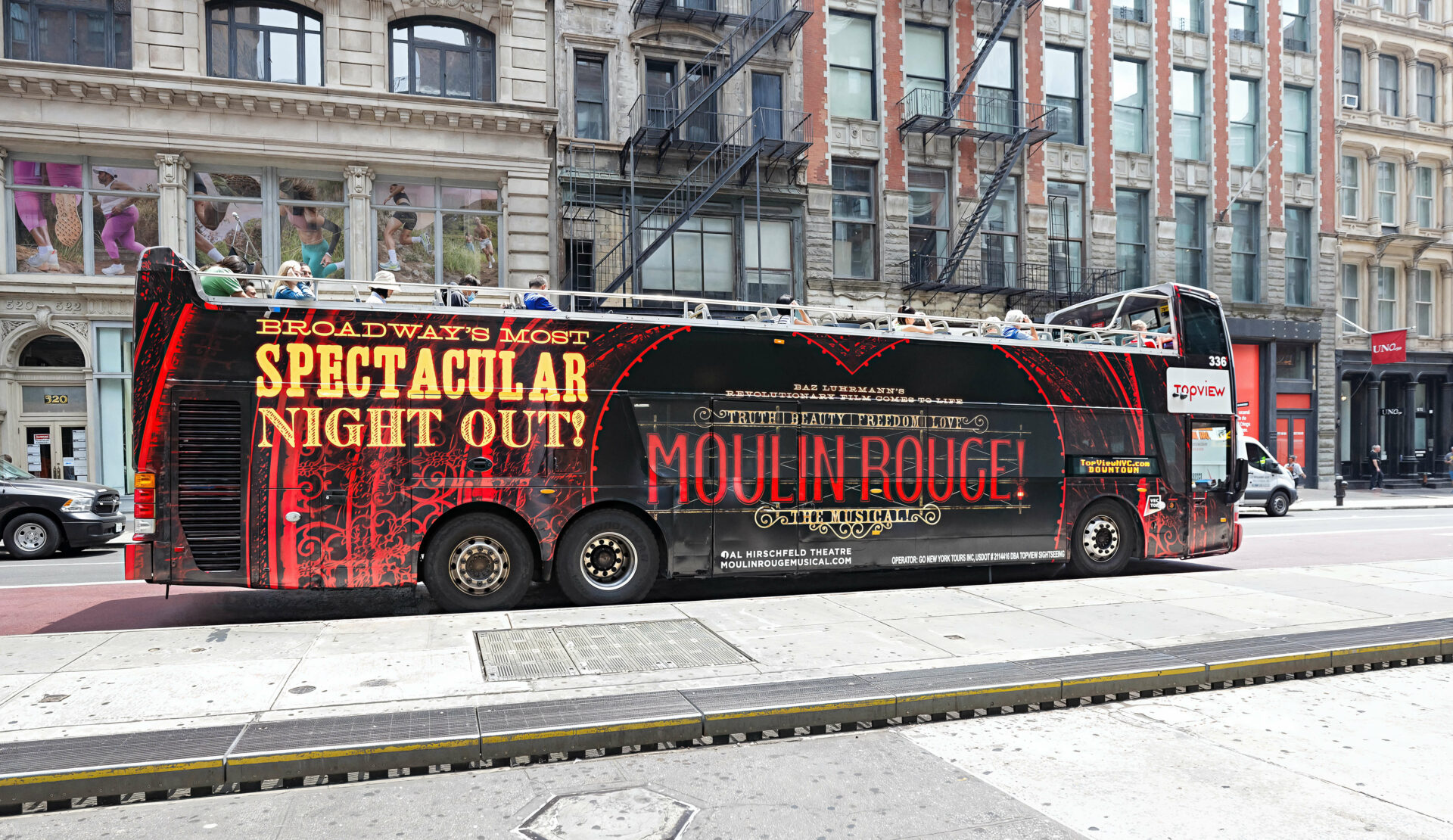 Double-decker bus wrapped with Moulin Rouge musical advertisements.