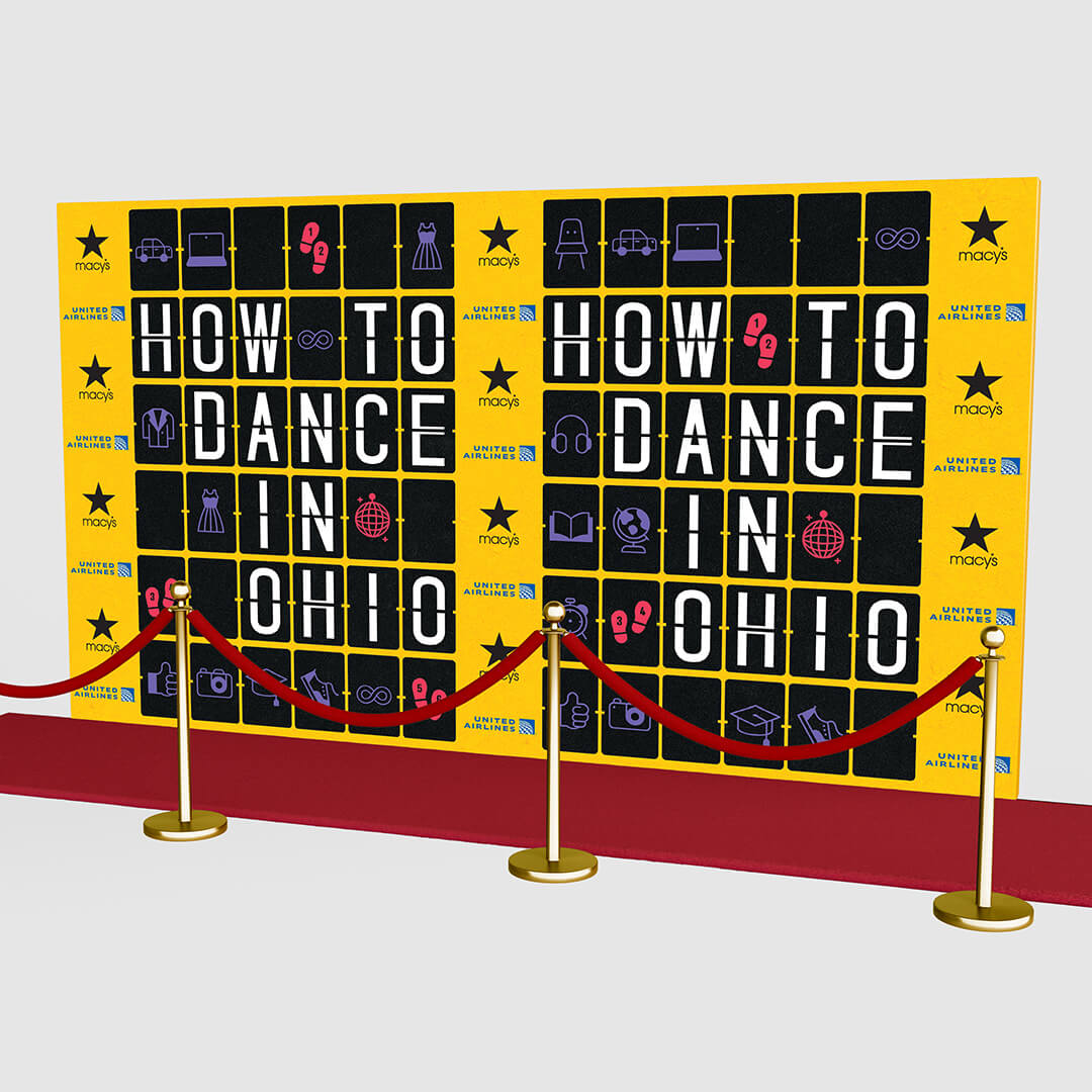 Yellow step-and-repeat backdrop for How to Dance in Ohio with a and red carpet.