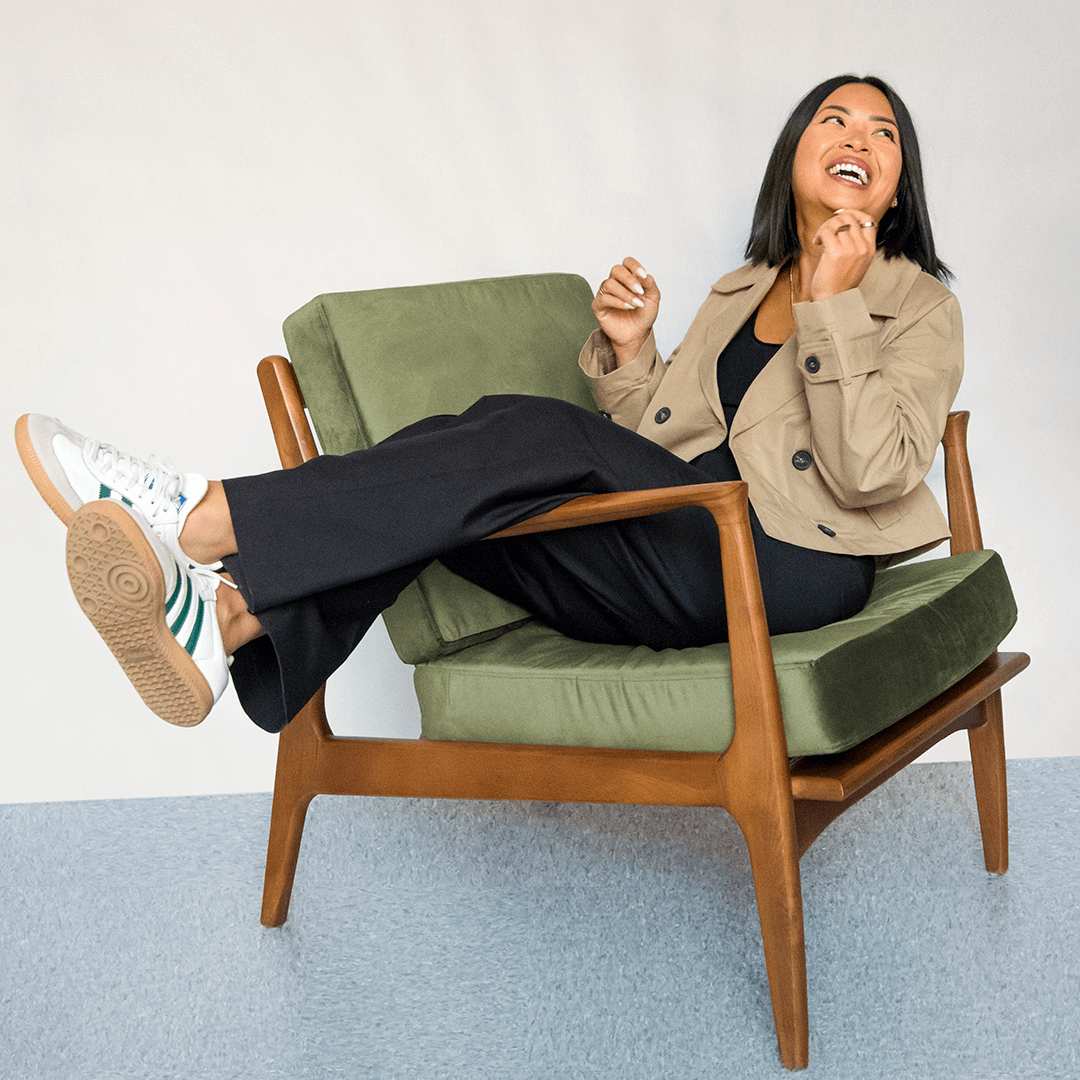 Phu Pham sitting and laughing in a green cushioned armchair.
